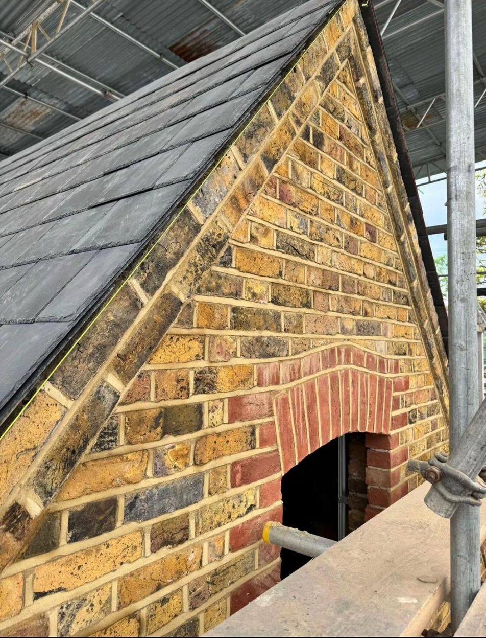 A rebuilt brick gable with decorative arched detail.